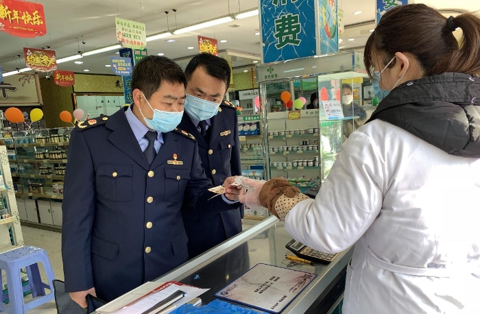 執(zhí)法人員在一家藥店檢查口罩質(zhì)量和進(jìn)銷價單據(jù)