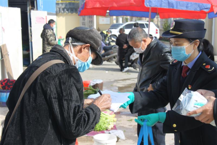 圖為鷹潭市市場監(jiān)管局工作人員向經(jīng)營戶發(fā)放口罩。