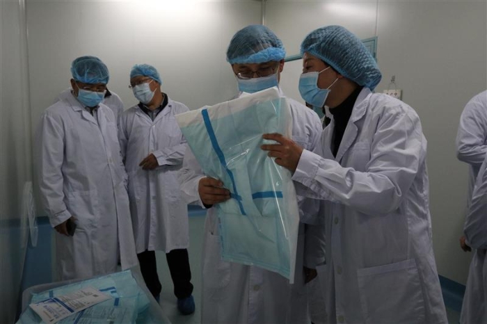 圖為云南省藥監(jiān)局黨組書記、局長劉本軍（右二）檢查該企業(yè)生產(chǎn)的醫(yī)用一次性防護(hù)服。（云南省藥監(jiān)局供圖）