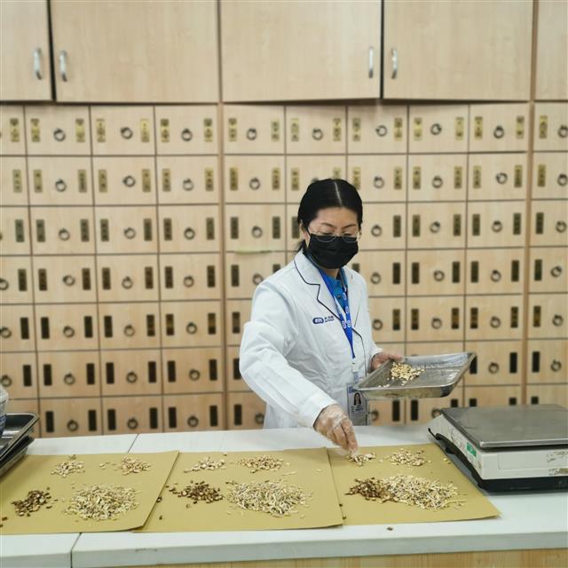 　侯惠鳴為顧客抓藥。