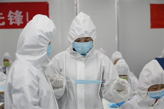 新疆維吾爾自治區(qū)藥監(jiān)局駐企特派員馬小華（右）正在與企業(yè)質(zhì)量負(fù)責(zé)人溝通口罩生產(chǎn)中遇到的問題。（馬少賓 攝）