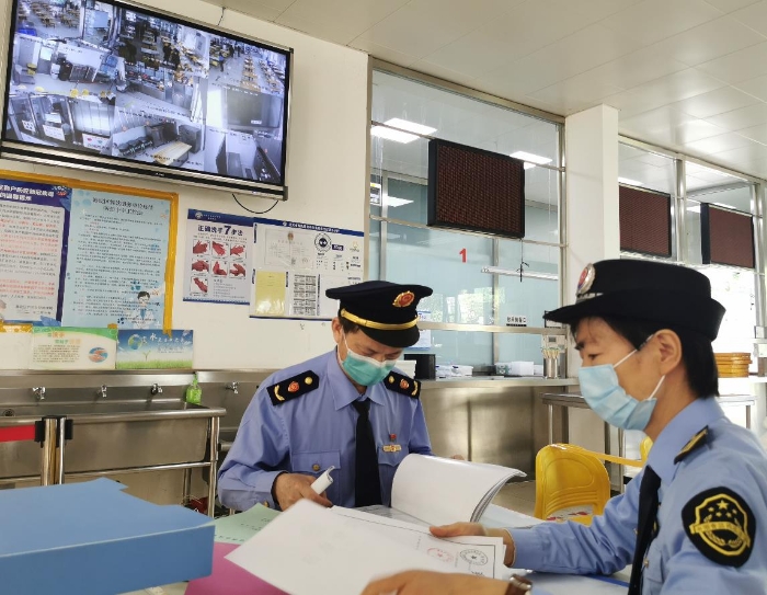 海淀區(qū)市場監(jiān)管局監(jiān)管人員檢查學校食堂進貨記錄。（中國食品藥品網(wǎng)記者王曉冬 攝）