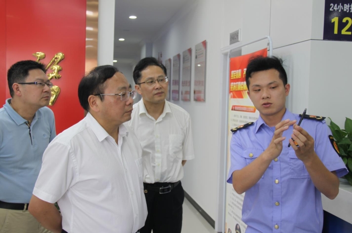 上官新晨（左二）在鷹潭市局東湖分局觀看基層執(zhí)法人員演示如何運(yùn)用智慧市場(chǎng)監(jiān)管網(wǎng)格化管理平臺(tái)開(kāi)展監(jiān)督檢查工作等情況。