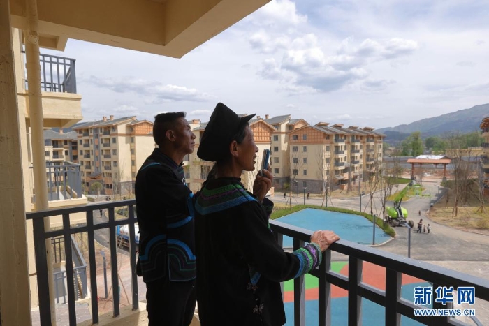 在四川省昭覺縣城易地扶貧搬遷安置點南坪社區(qū)，剛搬遷到新家的“懸崖村”村民莫色達(dá)體夫婦在陽臺給親戚打電話（2020年5月13日攝）。新華社記者 江宏景 攝