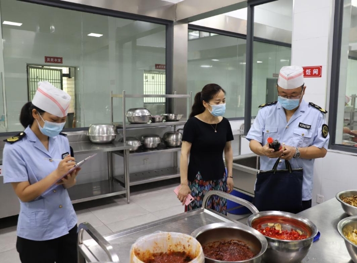 圖為執(zhí)法人員在檢查學(xué)校食堂加工制作情況。