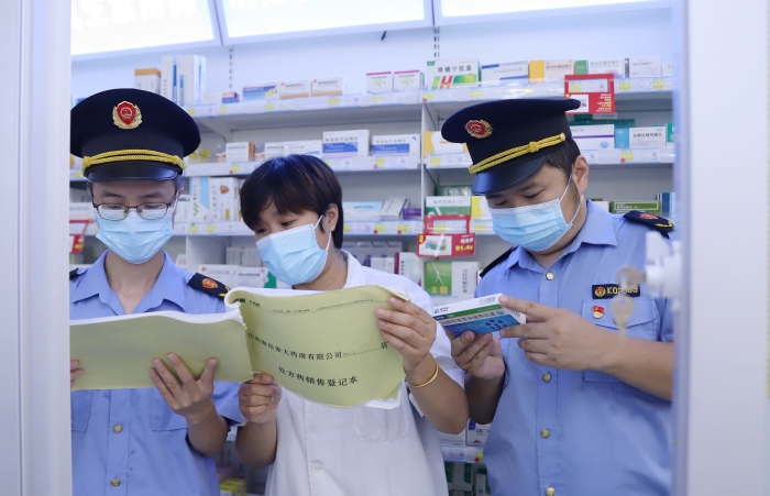 圖為9月13日執(zhí)法人員在一家藥店查看網(wǎng)絡(luò)藥品銷售登記情況，并核對處方藥處方單。
