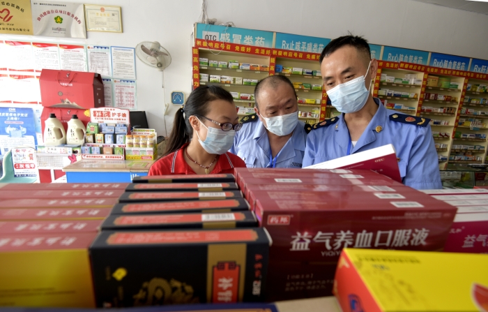 圖為執(zhí)法人員在一家藥店檢查中成藥質(zhì)量。