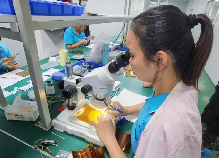 開蒙醫(yī)療員工在用顯微鏡檢查人體成分分析儀芯片上的箔片集成電路是否有缺陷。