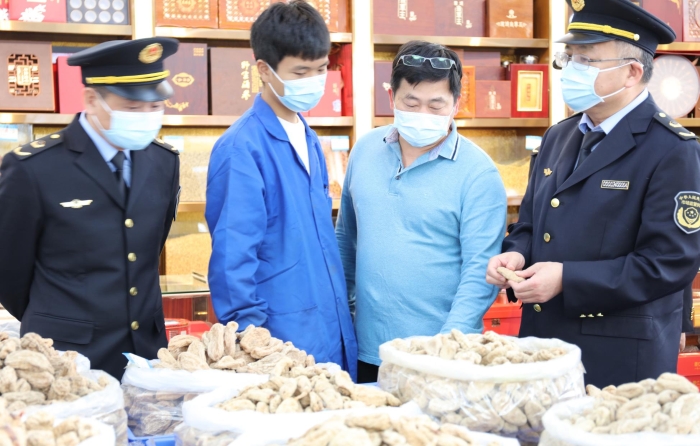 秦繼紅（右一）在中藥材市場門店查看。（喻燦華 攝）