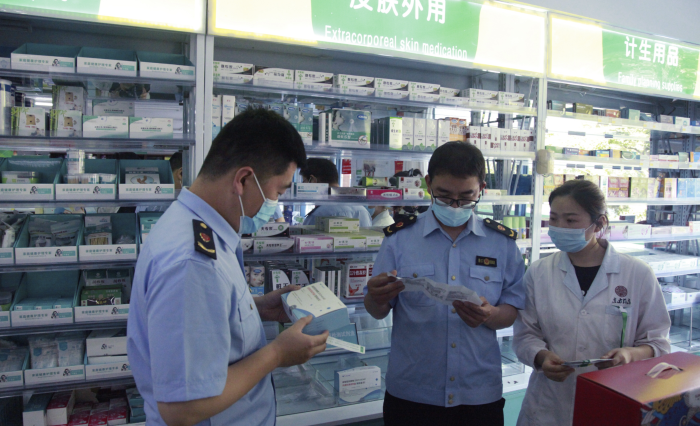 圖為青州市市場監(jiān)管局執(zhí)法人員在一家藥店檢查抗原檢測試劑盒質(zhì)量。