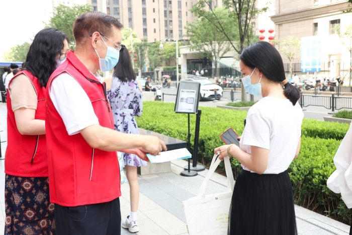 圖為藥監(jiān)系統(tǒng)志愿者為排隊等待檢測的居民發(fā)放科普抗疫小禮包，并為居民開展藥品安全科普，耐心解答居民用藥、用械安全方面的疑問和咨詢。（郝曉靜攝）