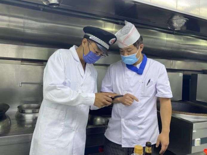 圖為海淀區(qū)市場監(jiān)管局執(zhí)法人員檢查學(xué)校食堂食品安全。