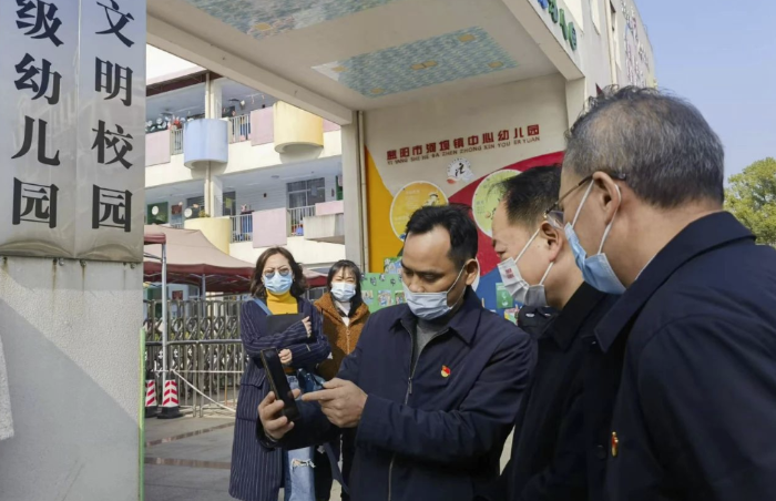 圖為樂運(yùn)成（右二）通過手機(jī)客戶端查看大通湖區(qū)第一實(shí)驗(yàn)幼兒園廚房實(shí)時(shí)視頻。