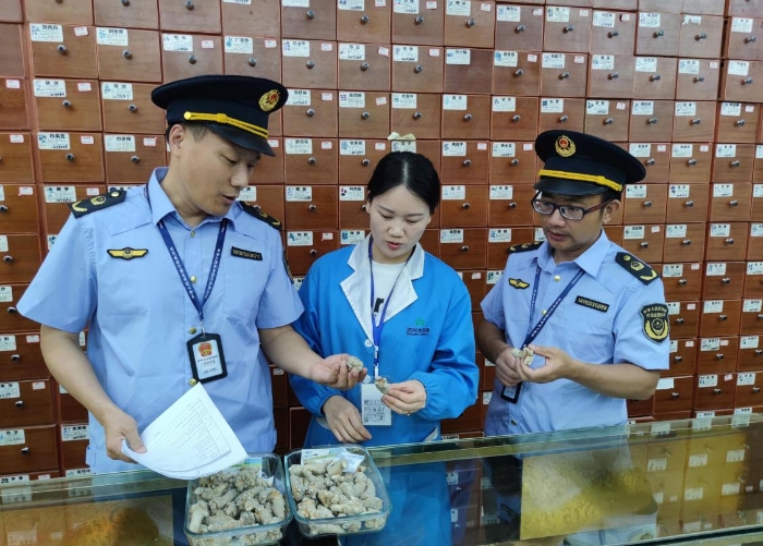 圖為執(zhí)法人員在一零售藥店檢查中藥飲片質(zhì)量情況。