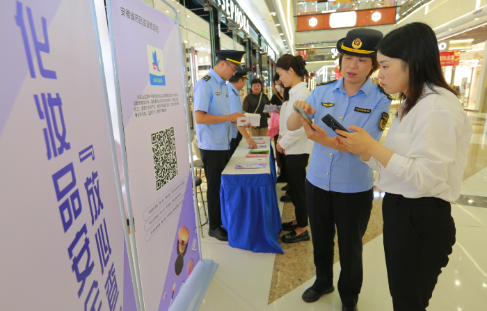 圖為9月13日，該局執(zhí)法人員正在指導(dǎo)化妝品經(jīng)營者安裝使用該APP。