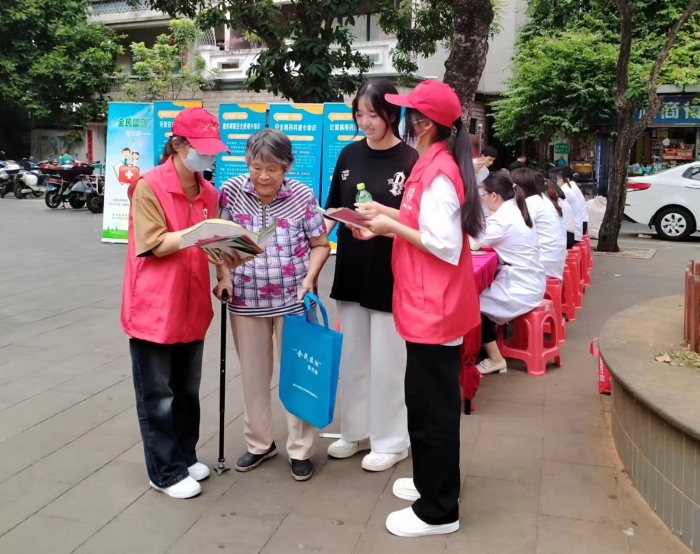 圖為工作人員向過往居民發(fā)放“全民監(jiān)測”科普宣傳資料。