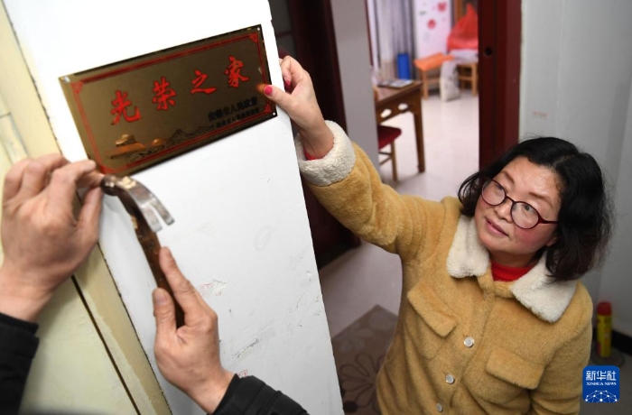 合肥市包河區(qū)常青街道工作人員在居民魏松梅（右）家門口懸掛“光榮之家”牌（2019年1月14日攝）。新華社記者 劉軍喜 攝